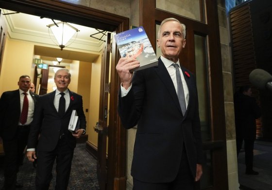 Prime Minister Mark Carney (right) holds up a copy of the budget as he and Minister of Finance and National Revenue Francois-Philippe Champagne make their way to the House of Commons earlier this month. (Justin Tang / The Canadian Press files)