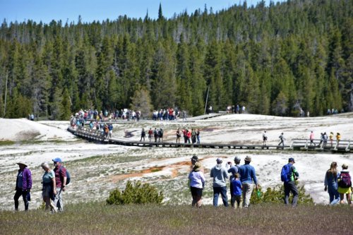 FILE - Tourists walk along a boardwalk in Upper Geyser Basin on June 22, 2022, in Yellowstone National Park, Wyo. (AP Photo/Matthew Brown, File)