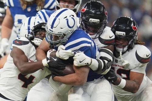 Indianapolis Colts running back Jonathan Taylor, center, is wrapped up by Houston Texans' Kamari Lassiter (4), Azeez Al-Shaair and Jaylen Reed (23) during the first half of an NFL football game Sunday, Nov. 30, 2025, in Indianapolis. (AP Photo/Michael Conroy)
