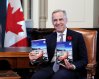 Prime Minister Mark Carney holds up copies of the budget before the tabling of the federal budget on Parliament Hill in Ottawa, on Tuesday, Nov. 4, 2025. THE CANADIAN PRESS/Justin Tang