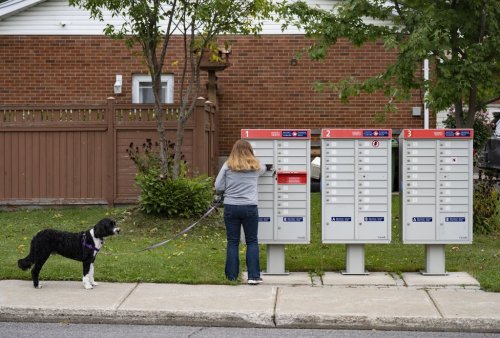 A woman checks for mail at her community mailbox in the Pointe-Claire neighbourhood of Montreal on Friday, Sept. 26, 2025. THE CANADIAN PRESS/Christinne Muschi