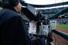 FILE - A sheet showing Boston Red Sox players photos hangs from a camera as a broadcast operator works during the first inning of a baseball game between the Baltimore Orioles and the Red Sox, Monday, April 24, 2023, in Baltimore, Md. (AP Photo/Julio Cortez, File)