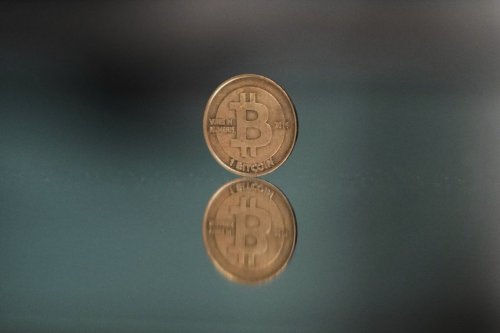 A bitcoin token is reflected on a mirror in Prague, Czech Republic, Sunday, May 11, 2025. (AP Photo/Petr David Josek)