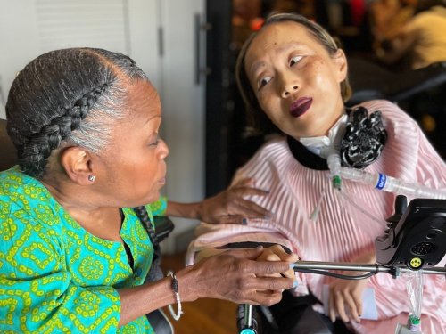 This March 2024 photo provided by Sandy Ho shows Yomi Young, left, speaking with Alice Wong at Wong's 50th birthday party in San Francisco. (Sandy Ho via AP)