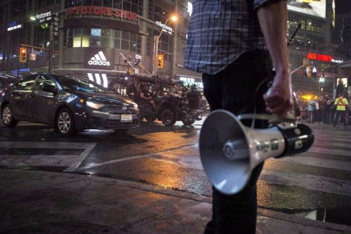 An assistant director stands by as a stunt car drives down Yonge Street during a film production in Toronto in 2015.  THE CANADIAN PRESS/Chris Young