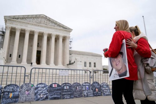 FILE - Jen Trejo holds a photo of her son Christopher as she is comforted outside the Supreme Court Dec. 4, 2023, in Washington. (AP Photo/Stephanie Scarbrough, File)