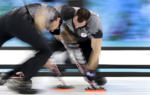 Canada's Ryan Harnden, left, and E.J. Harnden, right, sweep ahead of the rock during the men's curling gold medal game against Britain at the 2014 Winter Olympics on Feb. 21, 2014, in Sochi, Russia. (AP Photo/Wong Maye-E)
