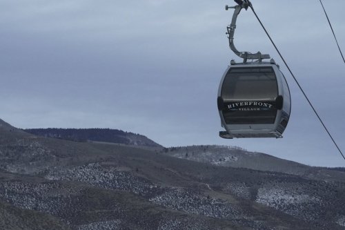 A gondola hangs in front of snow-scarce mountains Thursday, Dec. 18, 2025, in Avon, Colo. (AP Photo/Brittany Peterson)
