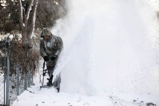 David Monias blows snow from the sidewalk on Valour Road on Thursday. (Mikaela MacKenzie / Free Press)