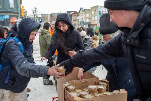 BROOK JONES/FREE PRESS
                                Volunteers Imtiaz Sidhu, Karen Kiss, and her son Miguel Kiss hand out soup and sandwiches to a person in need along Main Street near Logan Avenue on Christmas Day. They were among about 50 volunteers who participated in a community walk organized by OPK.
