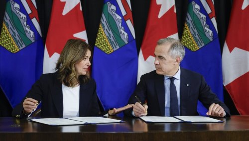 Prime Minister Mark Carney, right, signs a memorandum of understanding with Alberta Premier Danielle Smith in Calgary on Thursday, Nov. 27, 2025. THE CANADIAN PRESS/Jeff McIntosh