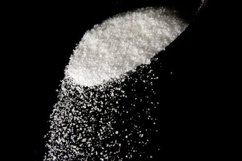 FILE - This photo illustration shows granulated sugar falling from a spoon, in Philadelphia, on Sept. 12, 2016. (AP Photo/Matt Rourke, File)