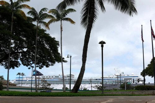 FILE - A cruise ship, background, is docked in Honolulu, March 23, 2020. (AP Photo/Caleb Jones, File)