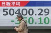 A person walks in front of an electronic stock board showing Japan's Nikkei index at a securities firm, Monday, Dec. 29, 2025, in Tokyo. (AP Photo/Eugene Hoshiko)