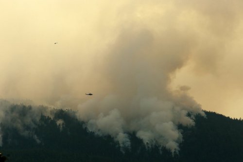 A helicopter flies by the Wesley Ridge wildfire near Cameron Lake where an out-of-control fire continues to burn near Coombs, B.C., Sunday, Aug. 3, 2025. THE CANADIAN PRESS/Chad Hipolito
