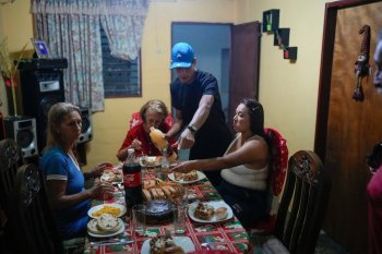 Mariela Gómez, right, and her partner Abraham Castro, a Venezuelan migrant couple, sit for Christmas dinner at Castro's parents' home in Maracay, Venezuela, early Thursday, Dec. 25, 2025. The couple abandoned their journey to the United States and returned home from Mexico by land and sea following President Donald Trump's immigration crackdown. (AP Photo/Matias Delacroix)