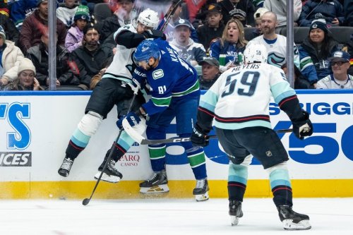 Vancouver Canucks' Evander Kane (91) hits Seattle Kraken's Adam Larsson (6) as Ben Meyers (59) watches during the second period of an NHL game in Vancouver, on Friday, January 2, 2026. THE CANADIAN PRESS/Ethan Cairns