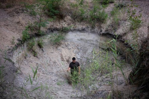 Oszkár Nagyapáti, farmer and member of the volunteer water guardians, stands in a hole in Kiskunmajsa, Hungary, Tuesday, July 29, 2025. (AP Photo/Denes Erdos)