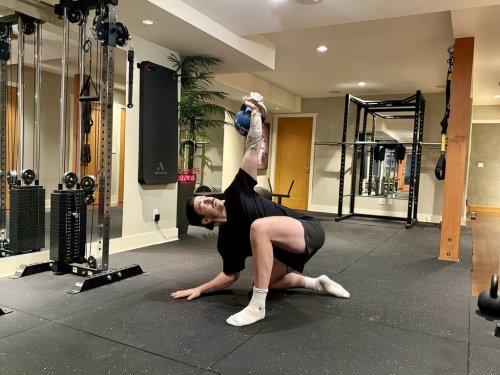 Cole MacCara, a personal trainer and founder of Vancouver's ColeMacFitness, demonstrates a Half Kneeling Kettlebell Windmill exercise, in this handout photo, in Vancouver, Dec. 14, 2025. THE CANADIAN PRESS/Handout - Cole MacCara (Mandatory Credit)