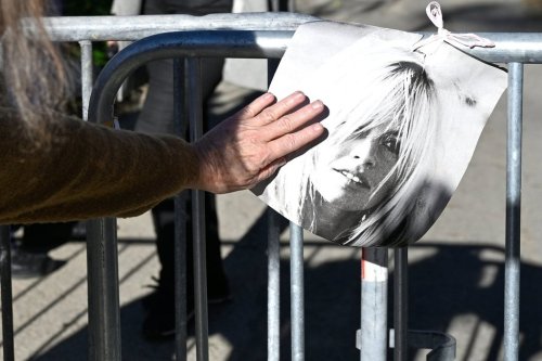 A woman touches a poster showing actor Brigitte Bardo near her home in Saint-Tropez, southern France, Sunday, Dec. 28, 2025 after the French 1960s sex symbol who became one of the greatest screen sirens of the 20th century and later a militant animal rights activist and far-right supporter, has died. She was 91. (AP Photo/Philippe Magoni)