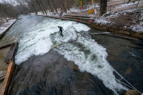 A man tries out the temporary Eisbach wave in the English Garden in Munich, Germany, Friday Dec. 26, 2025. (Peter Kneffel/dpa via AP)