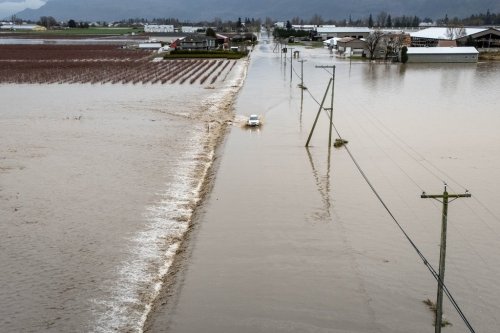 A car crosses a flooded street in Abbotsford B.C., on Thursday, Dec. 11, 2025. THE CANADIAN PRESS/Ethan Cairns