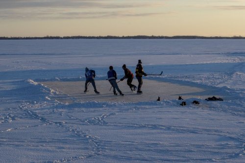 People play ice hockey on frozen Lake Ontario during sunset in Kingston, Ont., on Wednesday, Jan. 26, 2022. THE CANADIAN PRESS/Lars Hagberg