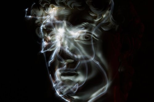 Stefania Terre, who is blind, uses a small light on her fingers while touching a life-size reproduction of the head of Michelangelo's David as she poses for a long-exposure photograph at the Omero Tactile Museum in Ancona, Italy, Thursday, Jan. 15, 2026. (AP Photo/Alessandra Tarantino)