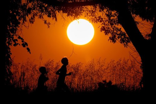 FILE - People are silhouetted against the sky at sunset as they run at Shawnee Mission Park, Sept. 26, 2024, in Shawnee, Kan. (AP Photo/Charlie Riedel, File)