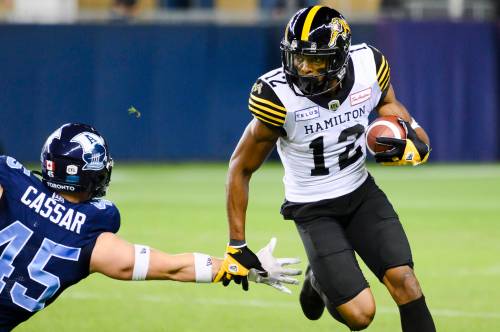 Hamilton Tiger-Cats wide receiver Tim White (12) runs downfield as Toronto Argonauts linebacker Jack Cassar (45) defends during second half CFL football action in Toronto on Friday, August 26, 2022. THE CANADIAN PRESS/Christopher Katsarov