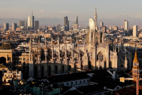 FILE - The pinnacles of the Duomo cathedral are lit by the afternoon declining sun and backdropped by the new Business Center in Milan, northern Italy, Jan. 4, 2017. (AP Photo/Luca Bruno, File)