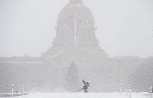 A worker blows snow in front of the Alberta Legislature during a heavy snowfall in Edmonton on Wednesday, Dec. 17, 2025. THE CANADIAN PRESS/Jason Franson