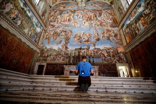FILE - A visitor kneels in front of the Last Judgement fresco by the Italian Renaissance painter Michelangelo inside the Sistine Chapel in Rome, May 3, 2021. (AP Photo/Alessandra Tarantino, File)