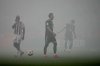 Bayern's Harry Kane, center, walks on the pitch covered in smoke from flares during the German Bundesliga soccer match between 1.FC Koeln and FC Bayern Munich in Cologne, Germany, Wednesday, Jan. 14, 2026. (AP Photo/Martin Meissner)