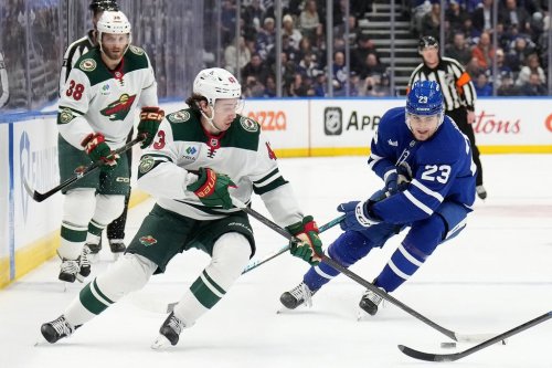 Minnesota Wild defenceman Quinn Hughes (43) and Maple Leafs forward Matthew Knies (23) vie for control of the puck in Toronto on Monday, Jan. 19, 2026. THE CANADIAN PRESS/Nathan Denette