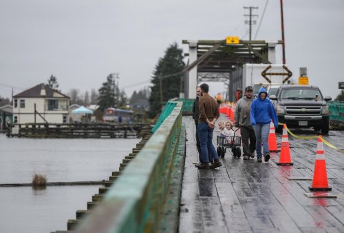 People walk across the Westham Island Bridge, which is closed to vehicle traffic after the span was hit by a tugboat last week, in Delta, B.C., on Wednesday, January 28, 2026. A bridge that provides the only road access to a Metro Vancouver island community has suffered more significant damage than originally thought and will take weeks for a permanent fix to be completed. THE CANADIAN PRESS/Darryl Dyck