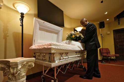 Wayne Bright, funeral director at Wilson Funeral Home, arranges flowers on a casket before a service Thursday, Sept. 2, 2021, in Tampa, Fla. (AP Photo/Chris O'Meara)