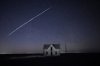 FILE - In this long exposure photo, a string of SpaceX StarLink satellites passes over an old stone house near Florence, Kan., on May 6, 2021. (AP Photo/Reed Hoffmann, File)