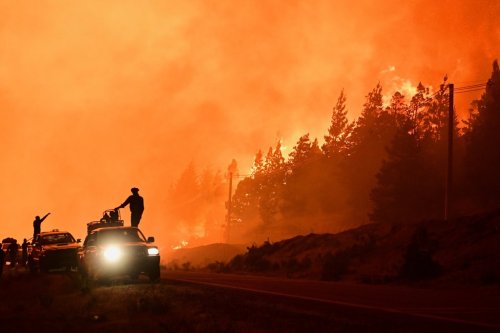 Firefighters stand on a truck as wildfires blaze in El Hoyo, Patagonia, Argentina, late Thursday, Jan. 8, 2026. (AP Photo/Maxi Jonas)