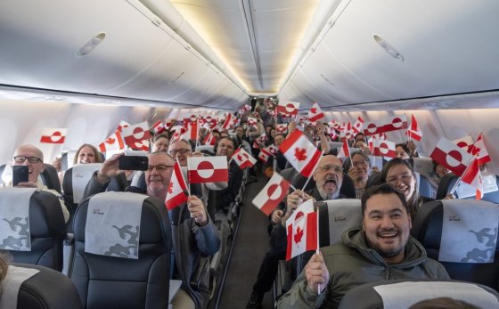Passengers on an Air Inuit flight wave flags as they travel from Montreal to Nuuk, Greenland on Feb. 5. (Christinne Muschi / The Canadian Press files)