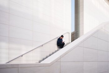 A woman checks phone sitting on a stairway outside a shopping mall in Beijing, China, Thursday, Jan. 15, 2026. (AP Photo/Vincent Thian)