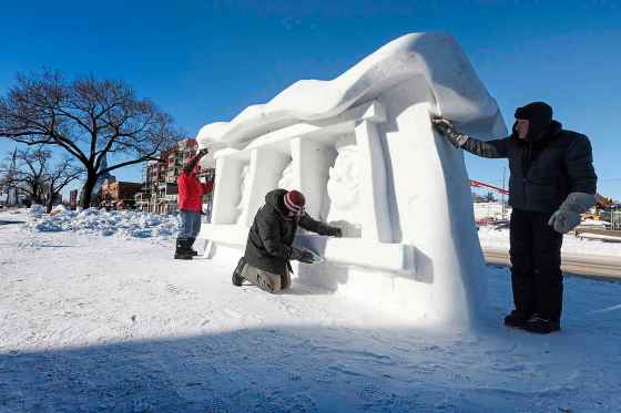 Local snow-sculpture artists Gary Tessier (from left), David MacNair and Jacques Boulet finish off the carving 'The Warmth of our Home' on Provencher Boulevard on Monday. They have more sculpting to do on the grounds of the Festival du Voyageur before it starts Feb. 13. (Ruth Bonneville / Free Press)