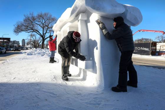 Gary Tessier (left, red), David MacNair (centre black) and Jacques Boulet (right) put the finishing touches on the snow sculpture The Warmth of our Home on Provencher Boulevard.(Ruth Bonneville / Free Press files)