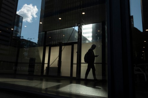 A man walks though a downtown Toronto office building with other buildings reflected in a window in this June 11, 2019 photo. THE CANADIAN PRESS/Graeme Roy