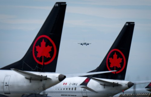 Air Canada aircraft sit parked at Vancouver International Airport as a United Airlines flight from Chicago prepares to land, in Richmond, B.C., on Monday, Aug. 18, 2025. THE CANADIAN PRESS/Darryl Dyck