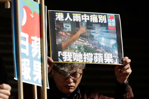 A Hong Kong activist in Taiwan holds a layout of Apply Daily during a protest to support Hong Kong activist publisher Jimmy Laiin Taipei, Taiwan, Tuesday, Feb. 10, 2026. A sign reads 