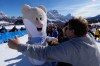 A spectator moves in to hug Olympic mascot Tina prior to an alpine ski women's downhill race, at the 2026 Winter Olympics, in Cortina d'Ampezzo, Italy, Sunday, Feb. 8, 2026.. (AP Photo/Robert F. Bukaty)