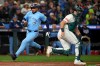 Toronto Blue Jays' Anthony Santander, left, scores on an RBI single by Ernie Clement during the fifth inning in Game 3 of baseball's American League Championship Series as Seattle Mariners catcher Cal Raleigh waits for the throw, Wednesday, Oct. 15, 2025, in Seattle. (AP Photo/Lindsey Wasson)