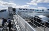 WestJet passengers deplane on the tarmac at Yellowknife Airport on Tuesday, July 22, 2025. THE CANADIAN PRESS/Jeff McIntosh