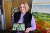 Ukrainian artist Iryna Prots shows a photo of 20-year old athlete Dariya Curdel who was killed in a Russian air attack — one of over 20 other Ukrainian athlete and coaches whose portraits were painted on the helmet of Ukrainian skeleton racer Vladyslav Heraskevych, in Kyiv, Ukraine, Thursday, Feb. 12, 2026. (AP Photo/Efrem Lukatsky)